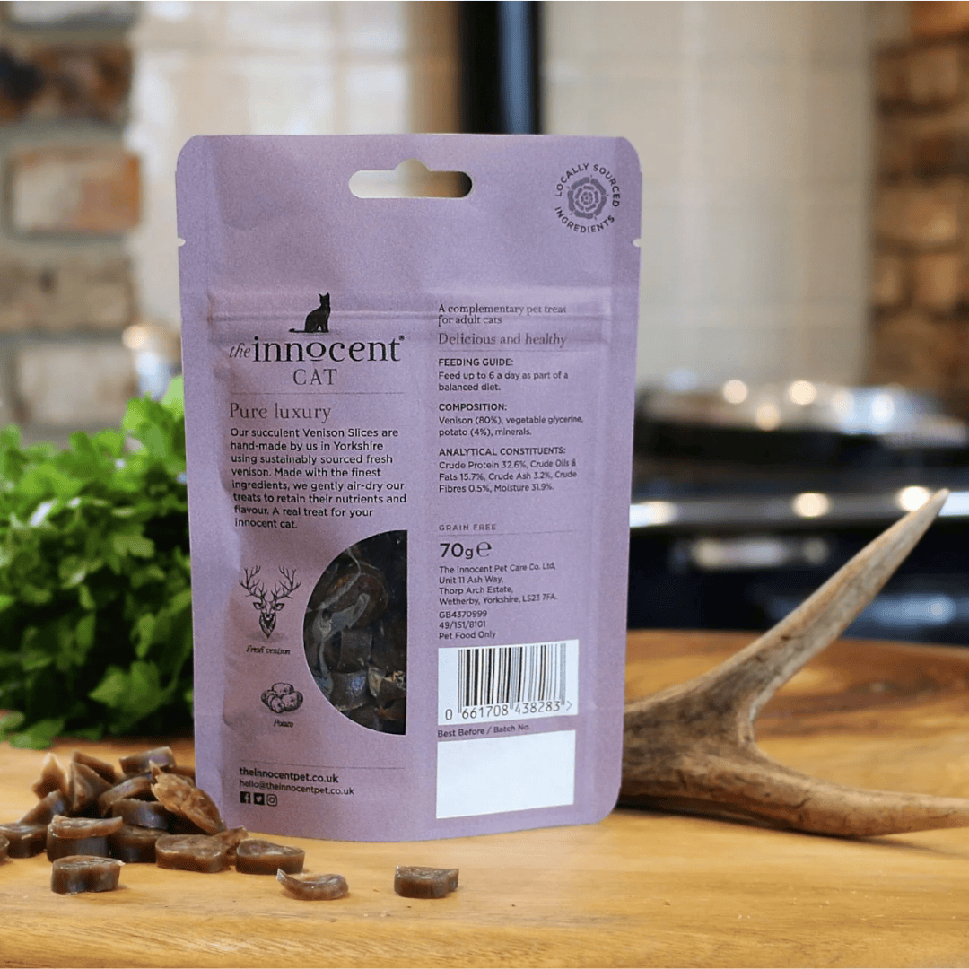The innocent cat venison slice with potato treats displayed loose beside their packaging and a deer antler.