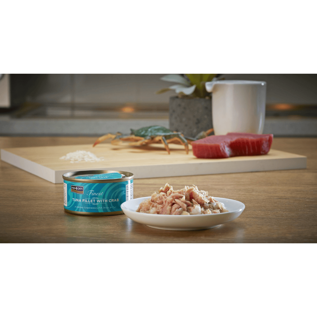 Canned tuna fillet with crab on a plate next to it's tin in a kitchen setting.