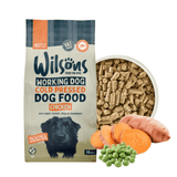 Wilson's Working Dog Cold Pressed Dog Food Chicken in a 15kg bag, shown next to a bowl of kibble, sweet potato, peas, and carrots on a white background.