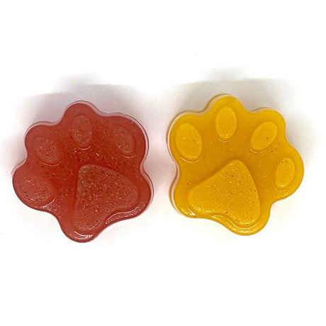 Two paw-shaped gummy treats, one red and one yellow, on a white background.