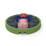A circular green textured pet puzzle feeder with multiple compartments containing dark gray, blue, pink and red paw and bone embossed pieces shown on a white background.