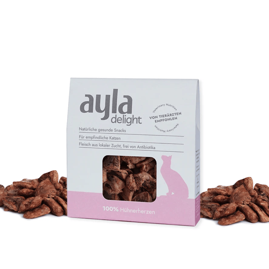 Box of ayla delight cat snacks with dried chicken hearts around it on a white background
