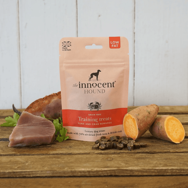 Bag of Innocent Hound Training Treats Tuna and Crab Rewards on a wooden surface, surrounded by raw ingredients and loose treats.