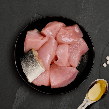 The fresh ingredients of the Canagan Chicken with Seabass Cat Food Tin 75g displayed on a plate.